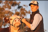 A yound woman stands holding a lead attached to a haltered cow.