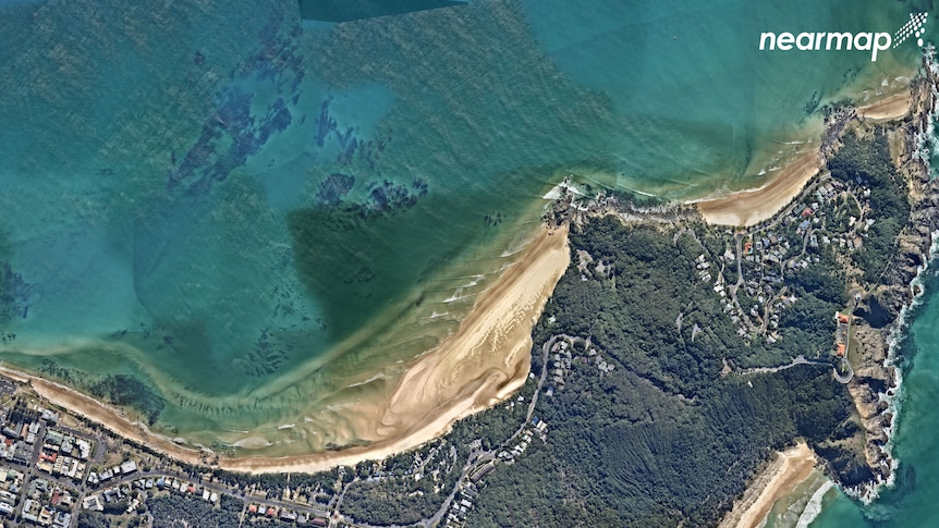 An aerial photo shows a concentration of sand in the water off a beach.