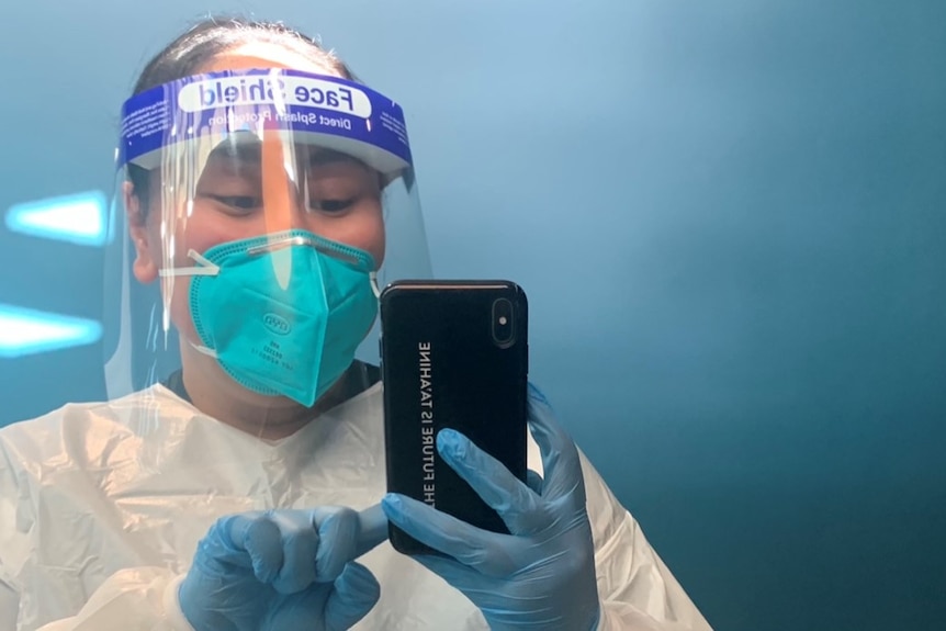 Shenei Meisi Penaia taking a selfie in front of the mirror in COVID PPE. 