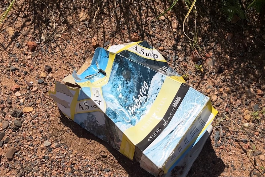 A cask wine case sits in the dirt. 