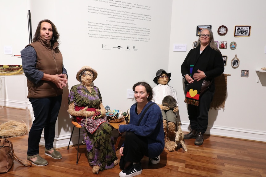 Three women of different ages from same family  stand with artworks in their exhibition