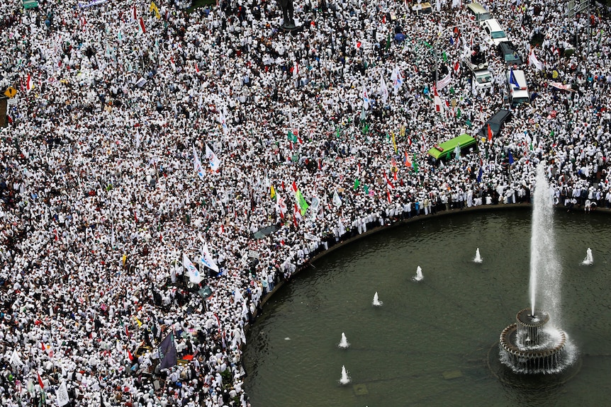 Thousands of people wearing white protest near a fountain
