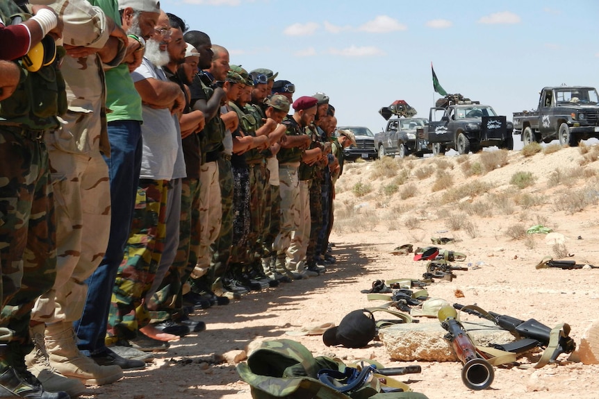 Anti-Gaddafi fighters pray as they prepare to advance on the besieged town of Bani Walid