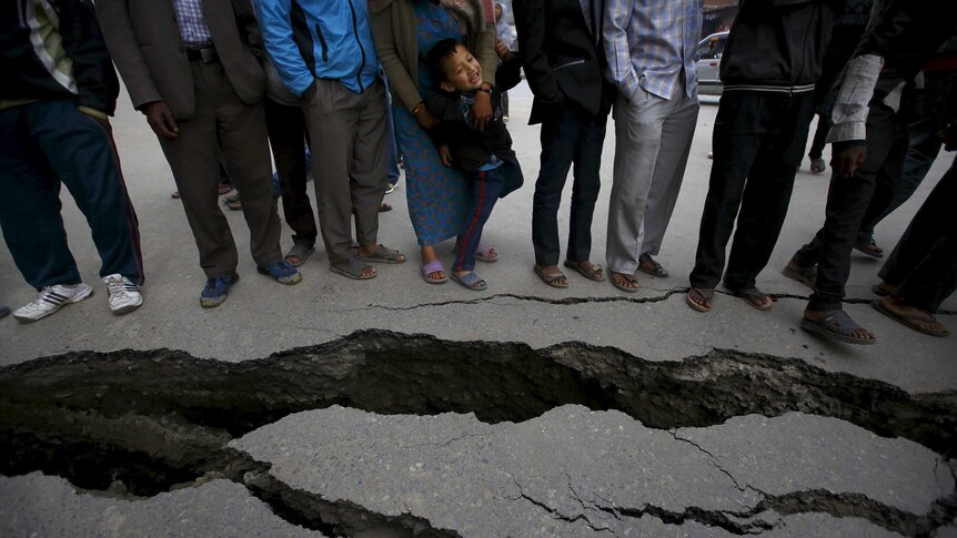 People gather near the cracks on the road caused by an earthquake in Bhaktapur,