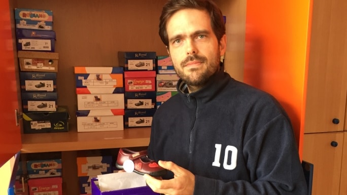 Athens shoe store owner Peter Voudouri holds shoes.