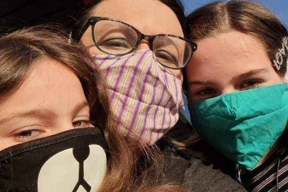 Cathy Barbagallo and her two daughters wearing colourful face masks in a selfie.