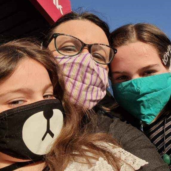 Cathy Barbagallo and her two daughters wearing colourful face masks in a selfie.