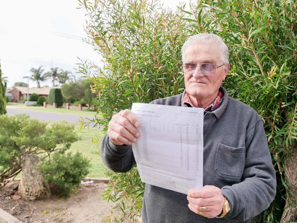 A man standing in front of bushes looking at a piece of paper