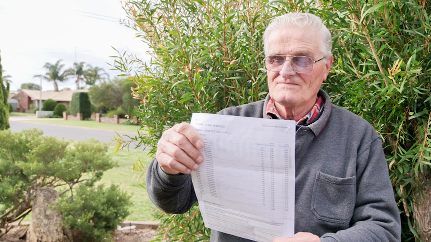 A man standing in front of bushes looking at a piece of paper