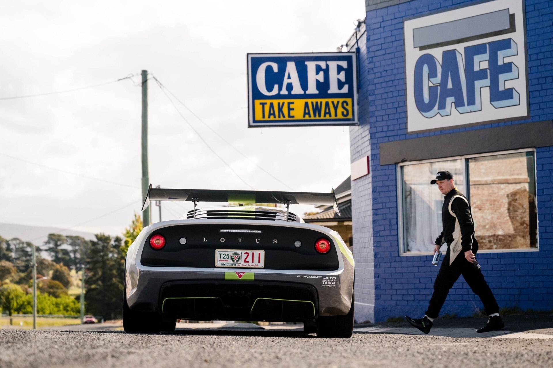 A white sports car parked outside of a dark blue cafe.