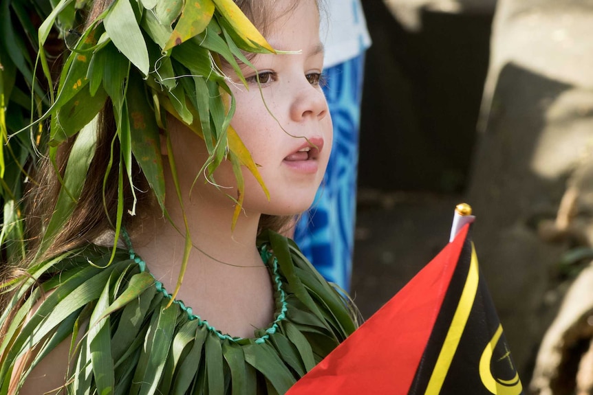 A young girl holds a Vanuatu national flag.
