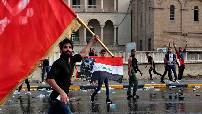 Protesters wave red, black and white flags as they run through Tahir Square