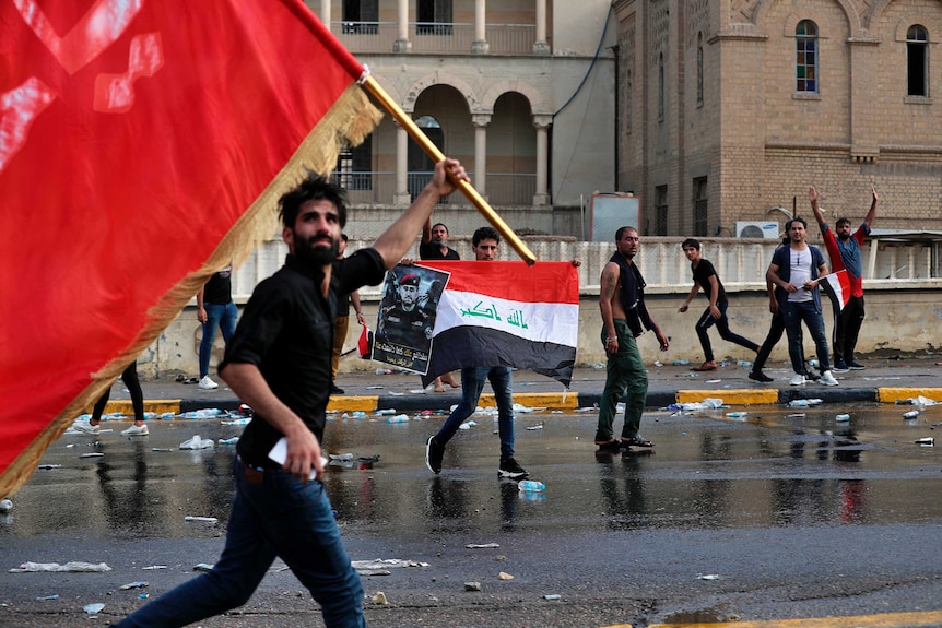 Protesters wave red, black and white flags as they run through Tahir Square