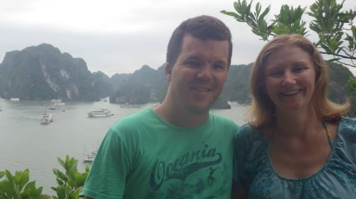 A young couple in front of ocean and mountains