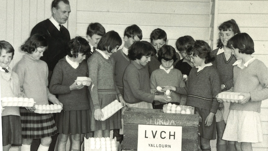 A black and white historical photo of a group of students with their teacher