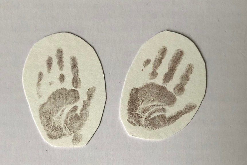 Three pieces of paper with a small baby's hand print and foot print 