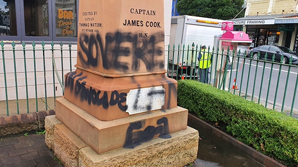 A large stone with the words "Captain James Cook" covered in black paint