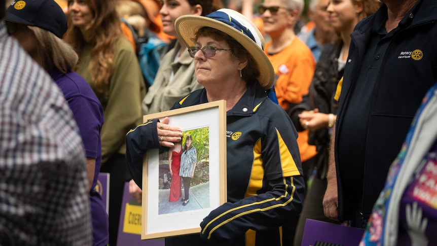 A woman holds a photo at a rally against domestic violence.