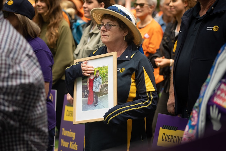 A woman holds a photo at a rally against domestic violence.