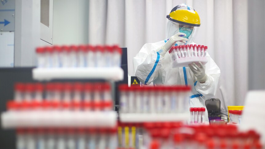 A medical staffer in PPE looks at vials at a testing laboratory in a Nanjing hospital on July 24, 2021