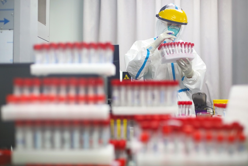 A medical staffer in PPE looks at vials at a testing laboratory in a Nanjing hospital on July 24, 2021