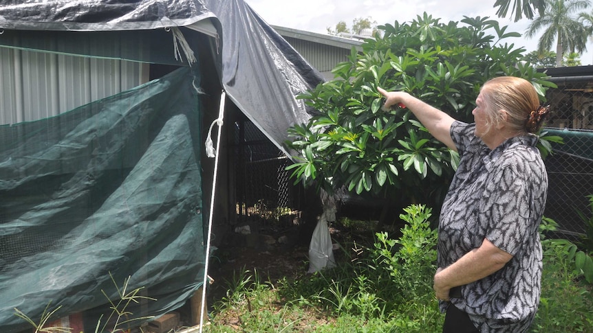 An elderly lady shows where her roof was repaired.