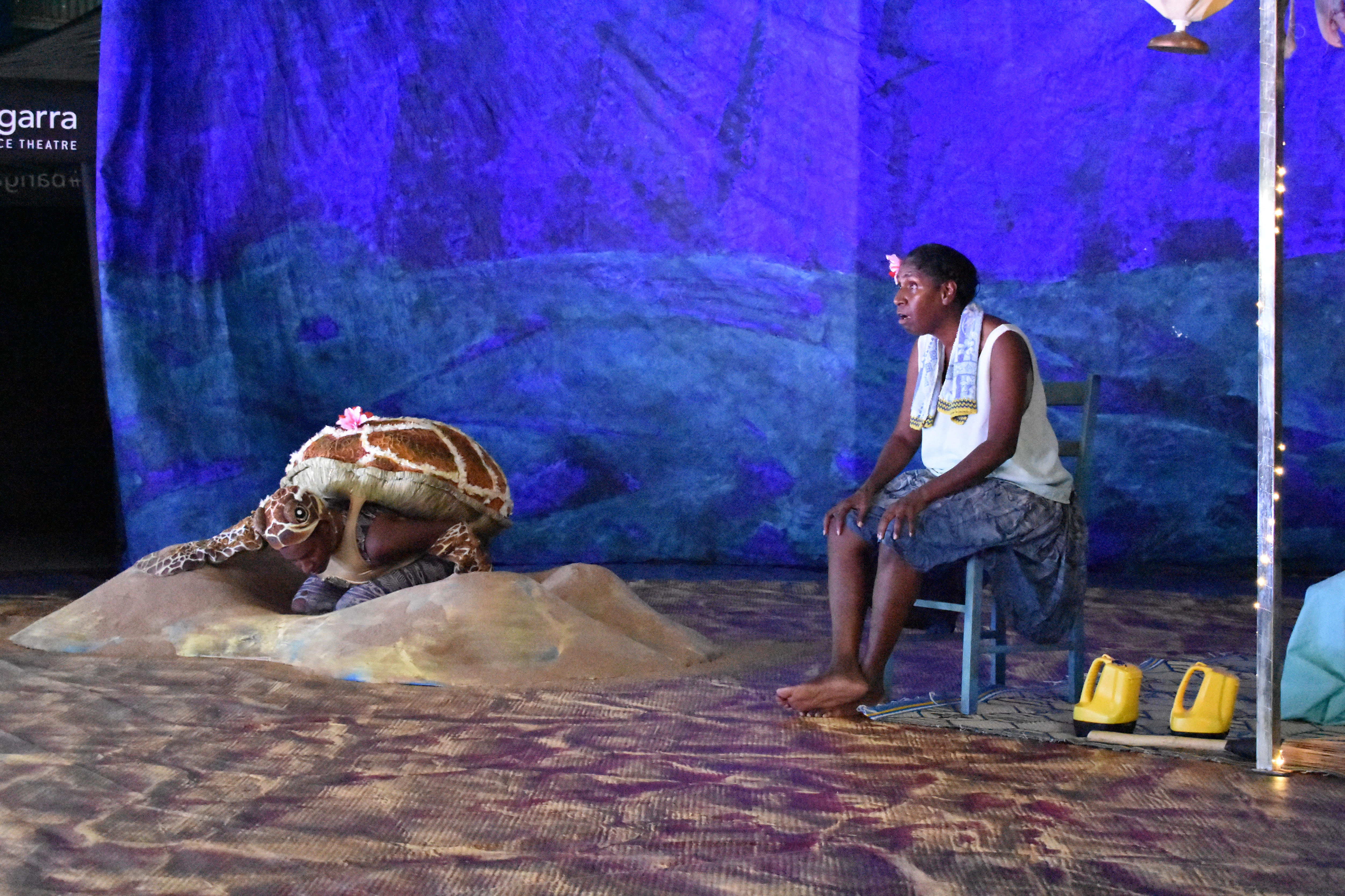 Elma Kris is performing on stage alongside a person dressed as a sea turtle.