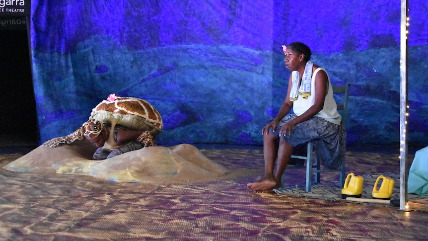 Elma Kris is performing on stage alongside a person dressed as a sea turtle.