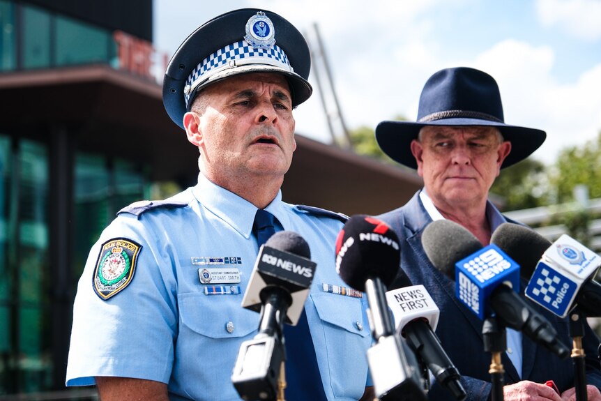 A police man and a man in a big hat giving a press conference