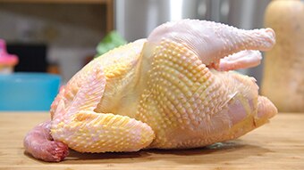 A raw chicken on a chopping board.