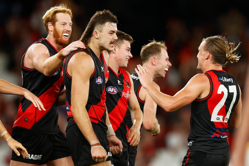 Sam Draper has a serious look on his face while teammates are happy around him