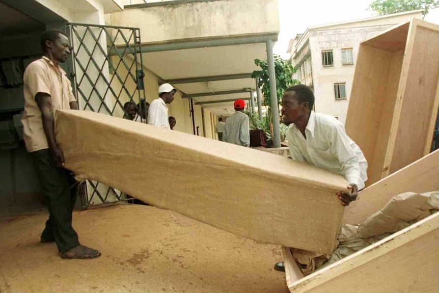 Two men load up coffins containing the bodies of tourists killed in Rwanda