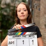 A young woman holding a clapper board