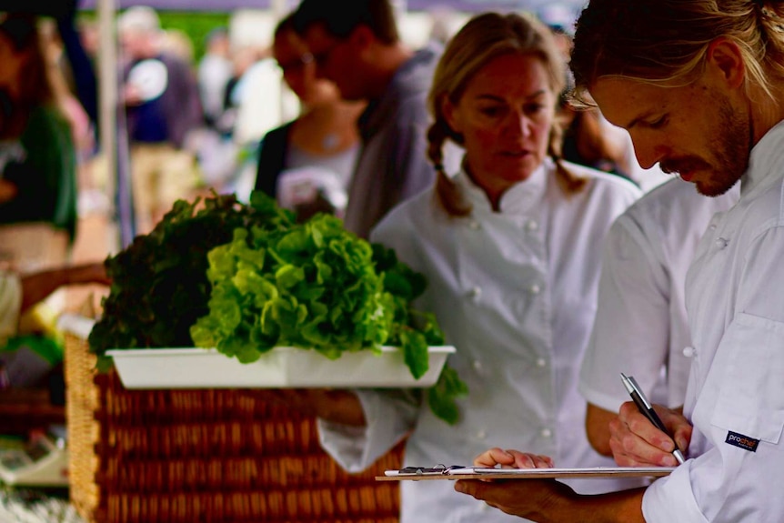 Students at the market taking notes about locally grown produce.