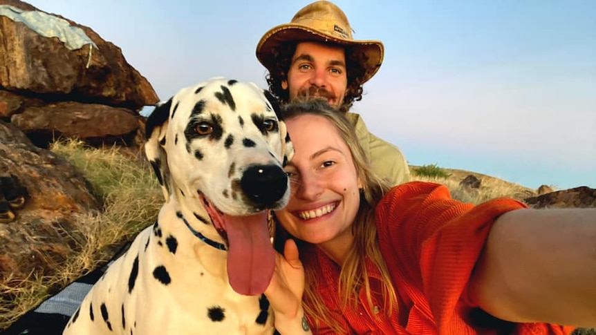 A woman, a dalmation and a man smiling outside.