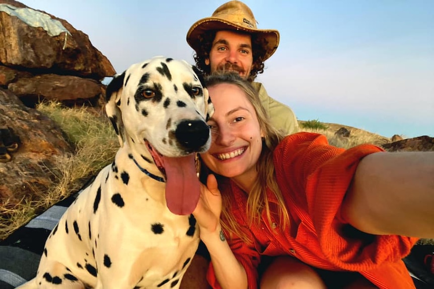 A woman, a dalmation and a man smiling outside.