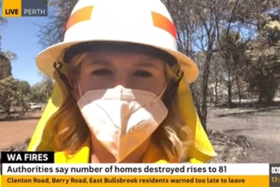 Woman wearing mask and fireman's hat with news graphics on screen around her.