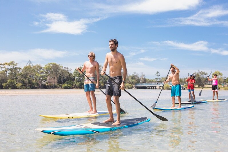 Stand-up paddle board tour group on Coffs Creek, led by Gymbanggirr man Clark Webb.