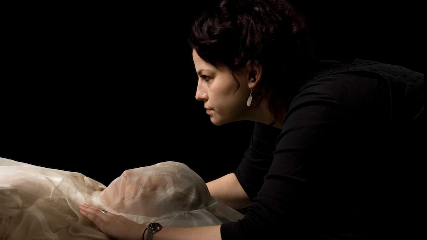 High-angle shot of Pia Interlandi covering a woman's feet in cotton shroud 'foot bag'.