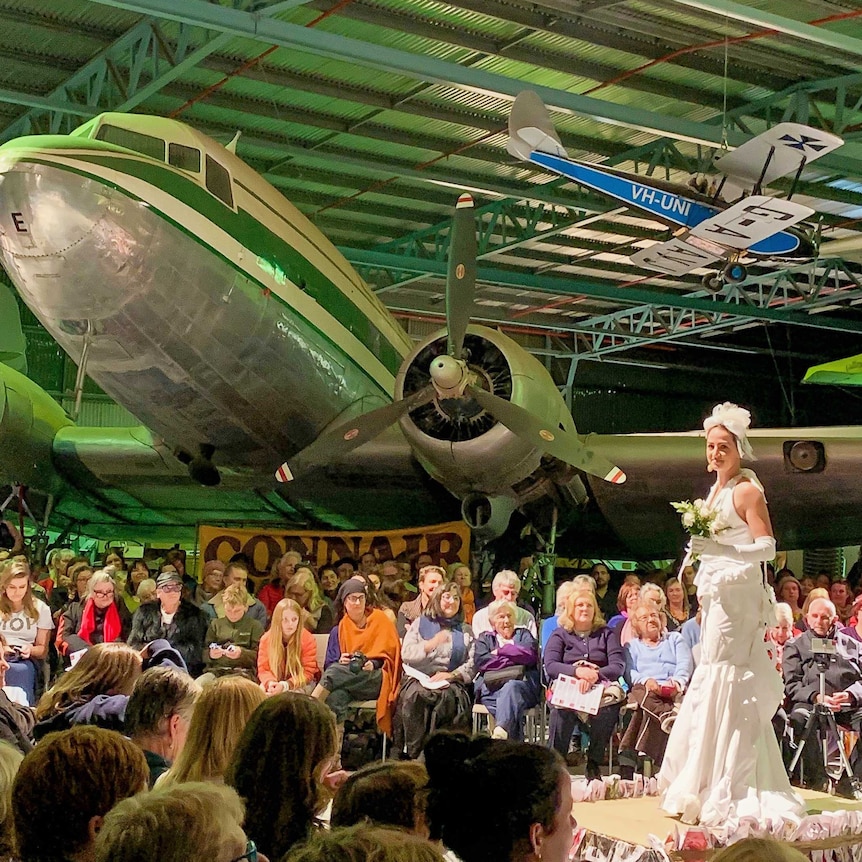 Sonja van Bavel modelling a wedding dress made from shirts on catwalk at Alice Aviation Museum