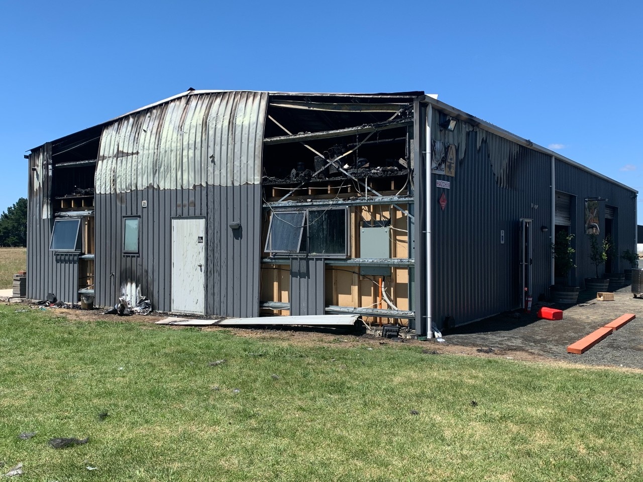 Lata curvada e madeira carbonizada no exterior de um grande galpão de lata