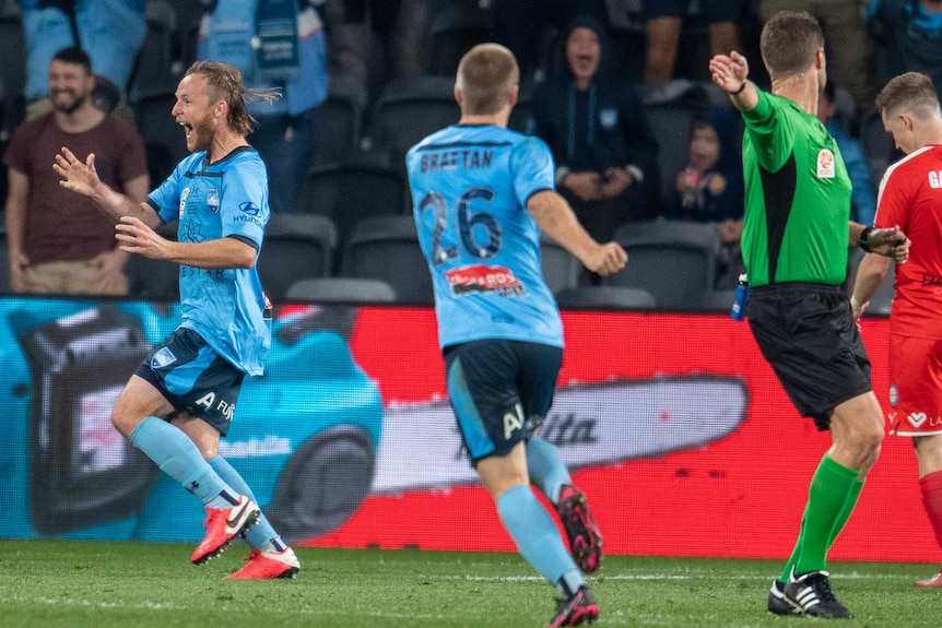 A Sydney FC A-League player runs to his left as he celebrates scoring a goal against Melbourne City in the grand final.