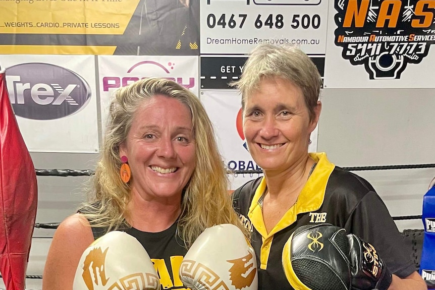 Victoria Vanstone in boxing gloves posing with a coach at a boxing ring, it's exercise she's embraced in her sobriety.