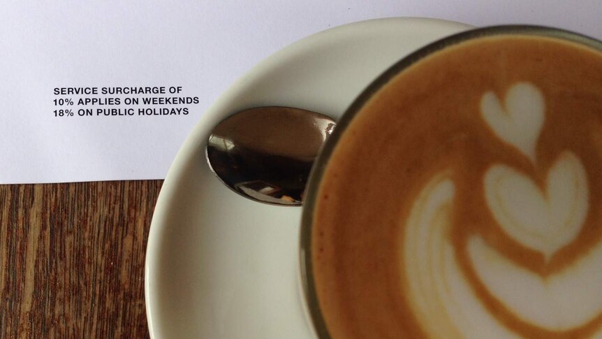 Image shows a cup of coffee and a menu noting surcharges of 10 percent for weekends and 18 per cent for public holidays apply.