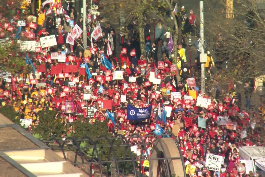 Helicopter perspective of a group of people in red holding signs 