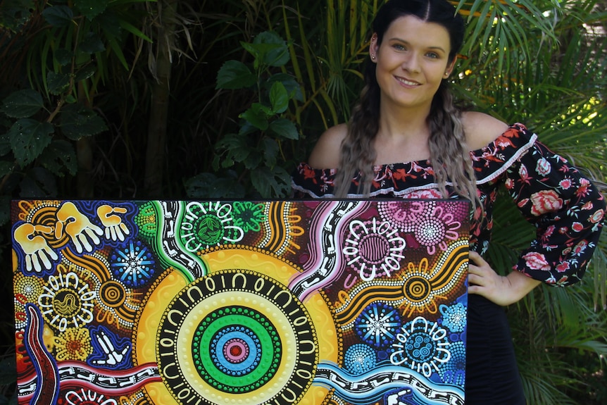 Artist Chern'ee Sutton holding her painting, titled "2023 World Cup," which FIFA will use in their tournament brand.