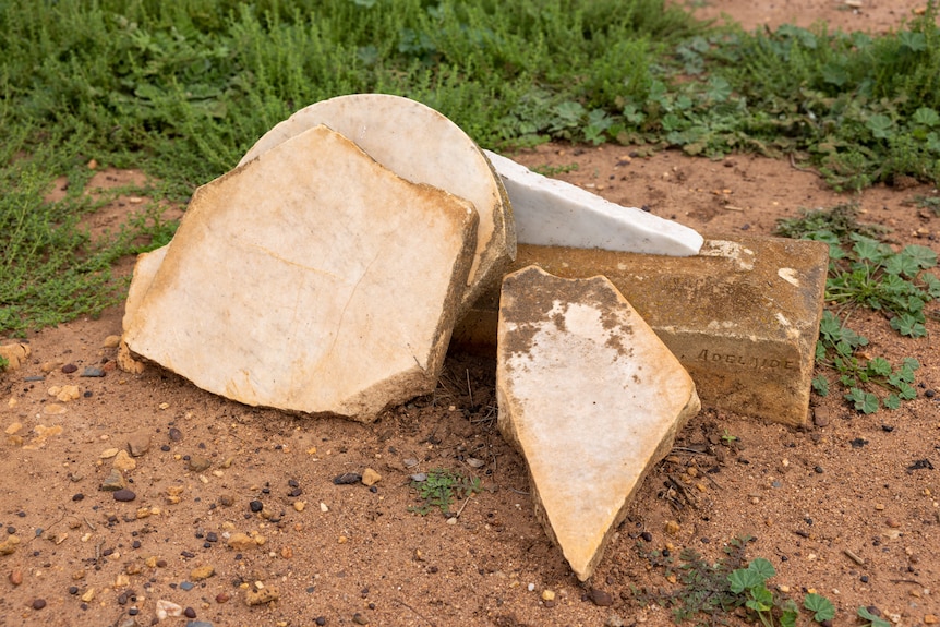 damaged tombstones sit in dirt