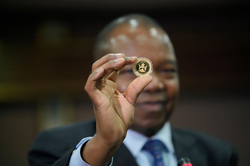 津巴布韦储备银行行长约翰·曼戈迪亚（John Mangodia）拿着一枚金币样本