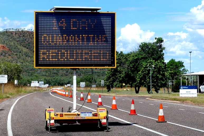 An LED border sign on a desert roadway. It reads: 14-day quarantine required