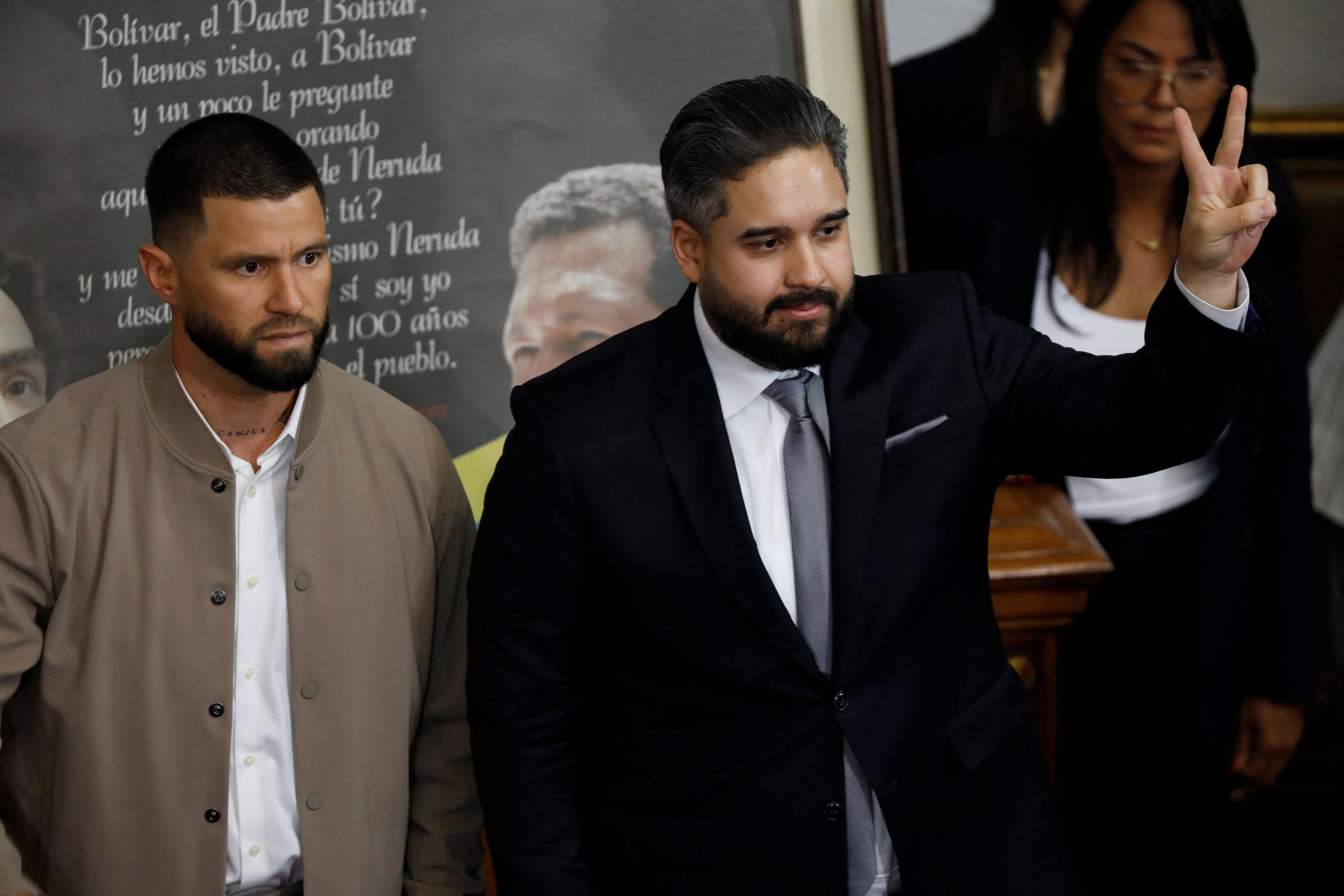 Un hombre de traje muestra un signo de la paz. 